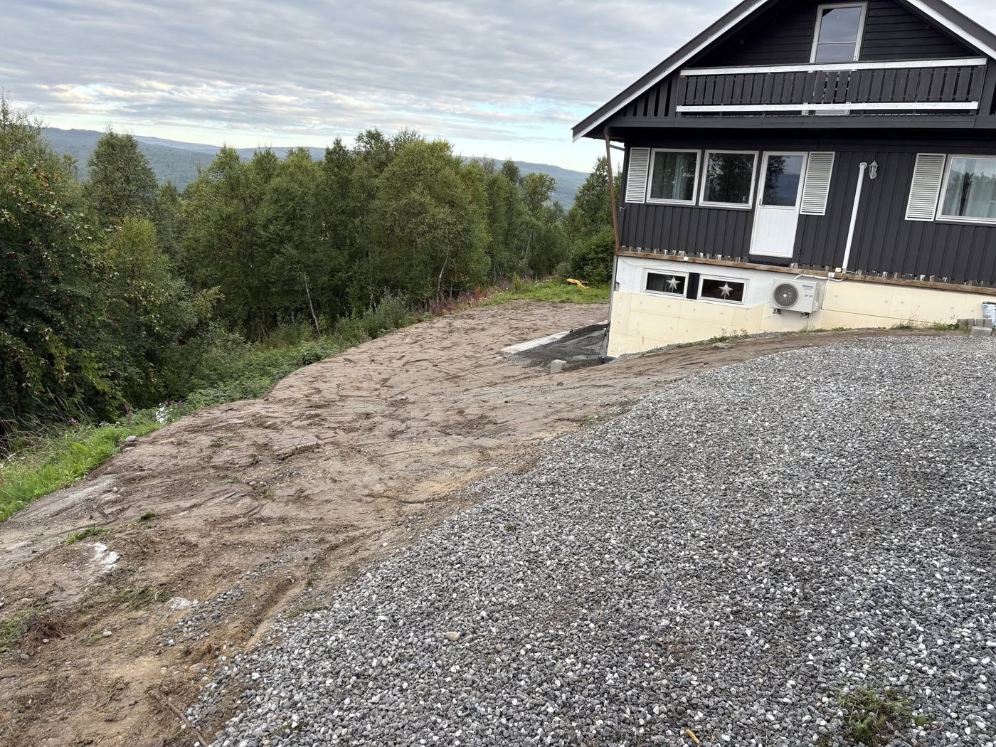 Planert tomt og oppkjørsel ved grått hus